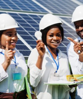 African american technician checks the maintenance of the solar panels. Group of three black engineers meeting at solar station. Hold led bulb.